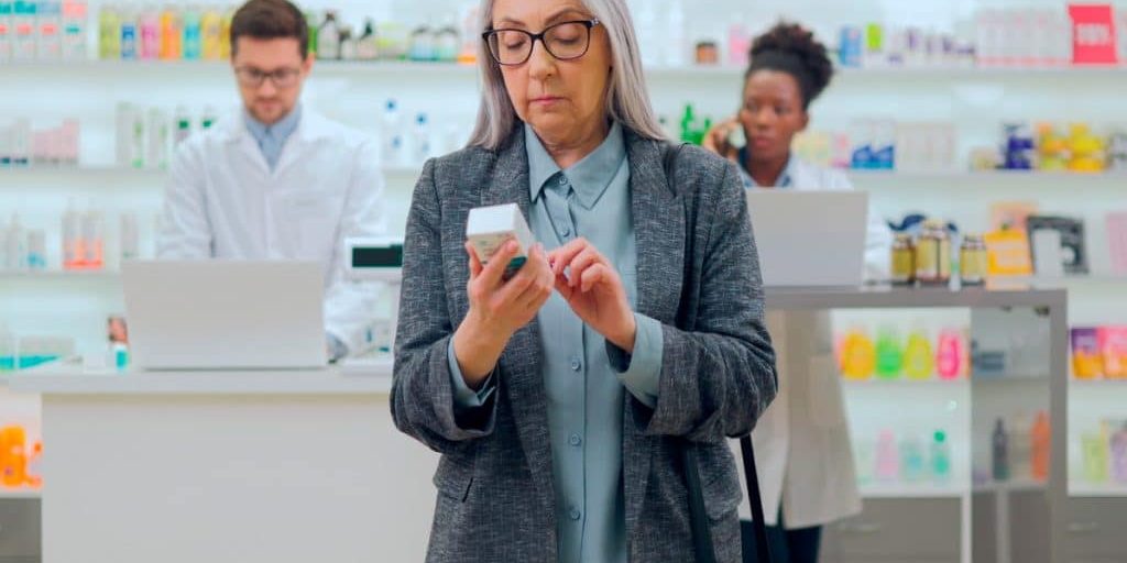 Senior woman checking to see the CBD expiration date on a box before buying.